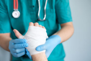 Questions to ask, close up of doctor bandaging one hand after an accident